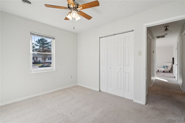 unfurnished bedroom with ceiling fan, a closet, and light carpet