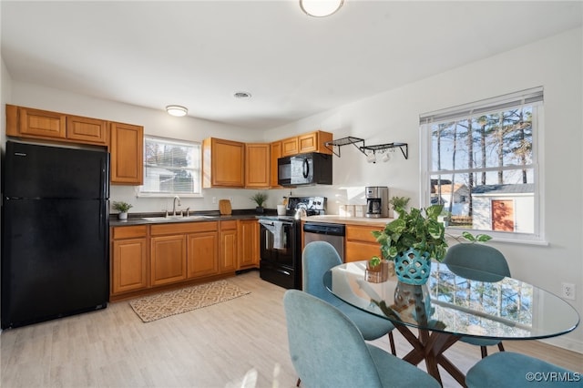 kitchen featuring light wood-type flooring, sink, plenty of natural light, and black appliances