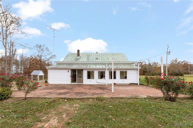 back of property with a lawn and a patio