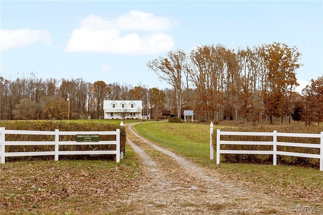 view of gate with a yard and a rural view