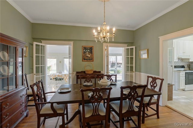 dining area featuring light wood-type flooring, crown molding, and a notable chandelier