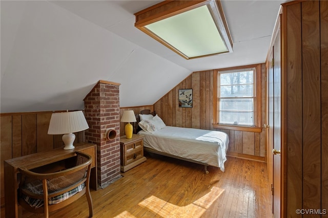 bedroom featuring wooden walls, light hardwood / wood-style flooring, and lofted ceiling