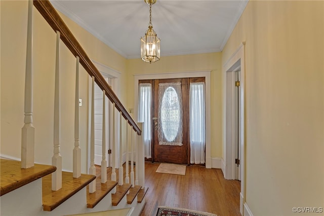 foyer entrance featuring light hardwood / wood-style flooring, a notable chandelier, and ornamental molding