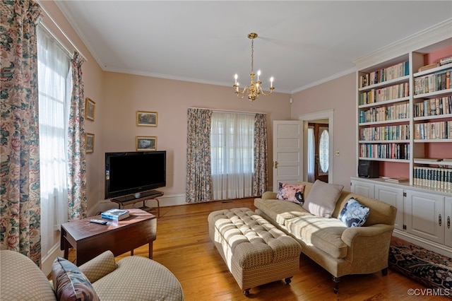 living room with a wealth of natural light, crown molding, an inviting chandelier, and light wood-type flooring