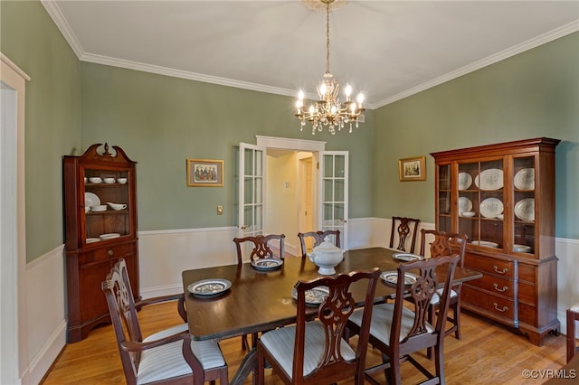 dining room with crown molding, light hardwood / wood-style floors, and a notable chandelier