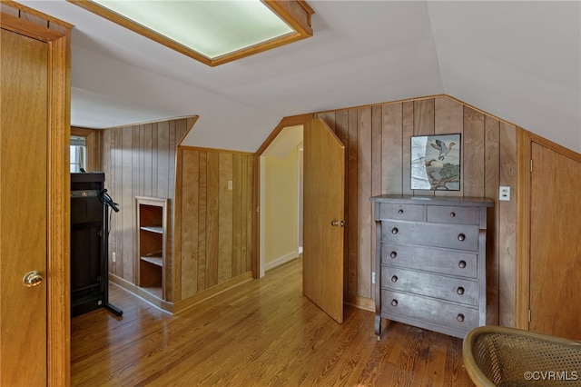 bonus room featuring wooden walls, light hardwood / wood-style floors, and lofted ceiling