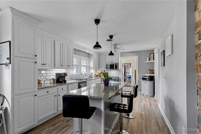 kitchen featuring a kitchen island, dark stone countertops, white cabinetry, and appliances with stainless steel finishes