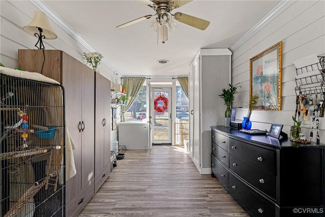 interior space with wooden walls, light hardwood / wood-style flooring, and ornamental molding