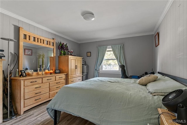 bedroom featuring crown molding, wooden walls, and light wood-type flooring