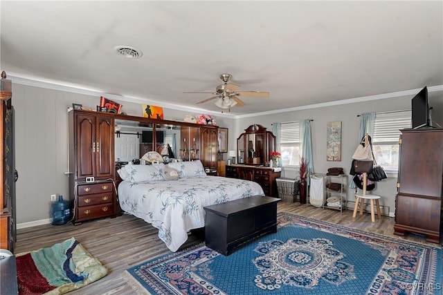 bedroom featuring hardwood / wood-style floors, ceiling fan, ornamental molding, and a baseboard heating unit