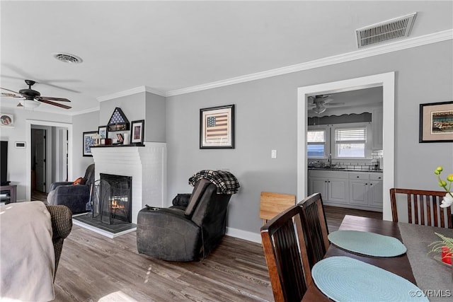 dining area featuring hardwood / wood-style flooring, ceiling fan, ornamental molding, and sink