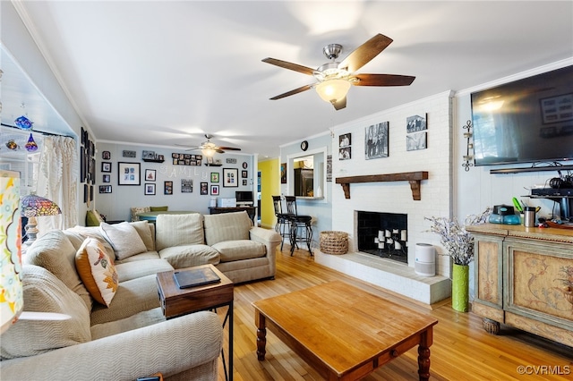 living room with hardwood / wood-style floors, ceiling fan, ornamental molding, and a fireplace