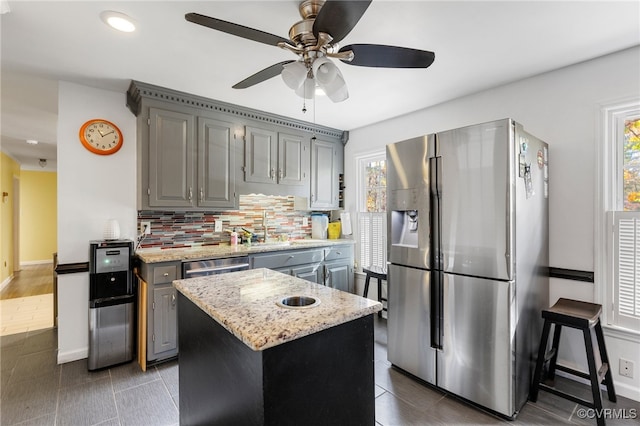 kitchen featuring ceiling fan, plenty of natural light, a kitchen island, and appliances with stainless steel finishes