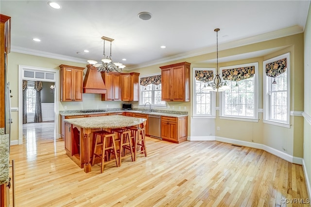 kitchen with a center island, light hardwood / wood-style flooring, crown molding, a breakfast bar area, and appliances with stainless steel finishes