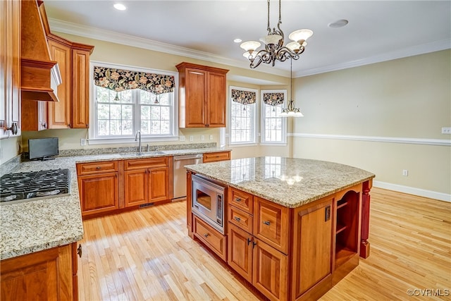 kitchen featuring light stone countertops, a center island, stainless steel appliances, crown molding, and light wood-type flooring