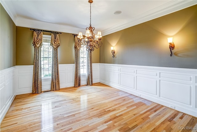 spare room with a chandelier, crown molding, and light hardwood / wood-style flooring