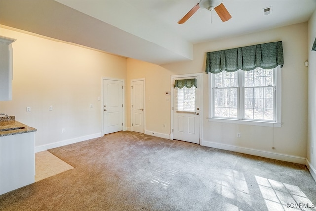 unfurnished living room with ceiling fan, sink, and light colored carpet