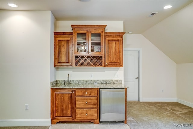 bar featuring stainless steel refrigerator, light stone countertops, light colored carpet, and lofted ceiling