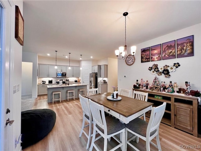 dining area featuring sink, a chandelier, and light hardwood / wood-style flooring