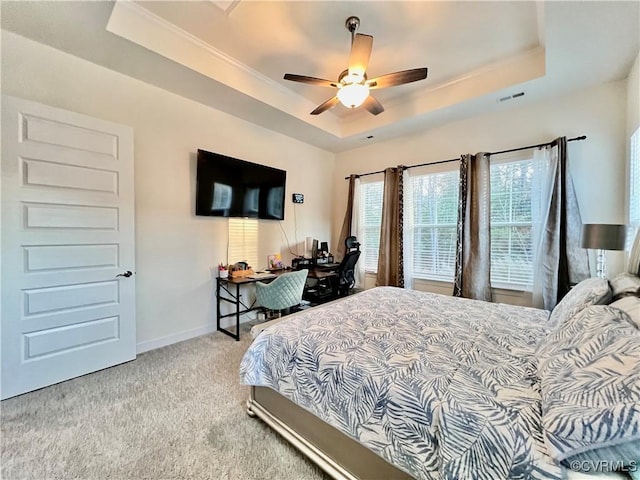 carpeted bedroom with a raised ceiling and ceiling fan