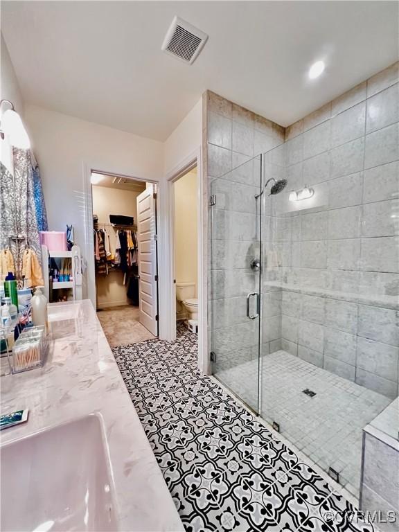 bathroom featuring vanity, an enclosed shower, and toilet