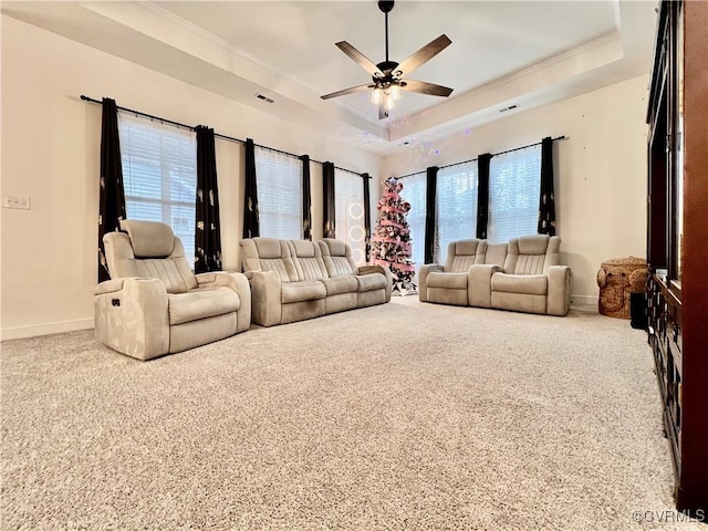 living room with a tray ceiling, light colored carpet, and ceiling fan