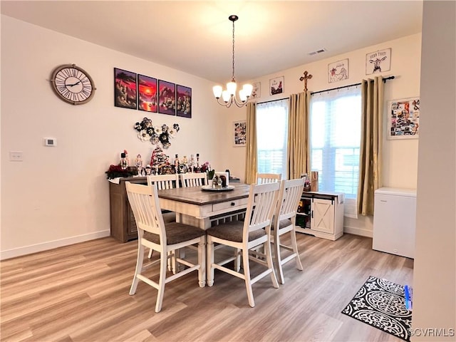 dining space with a notable chandelier and light wood-type flooring