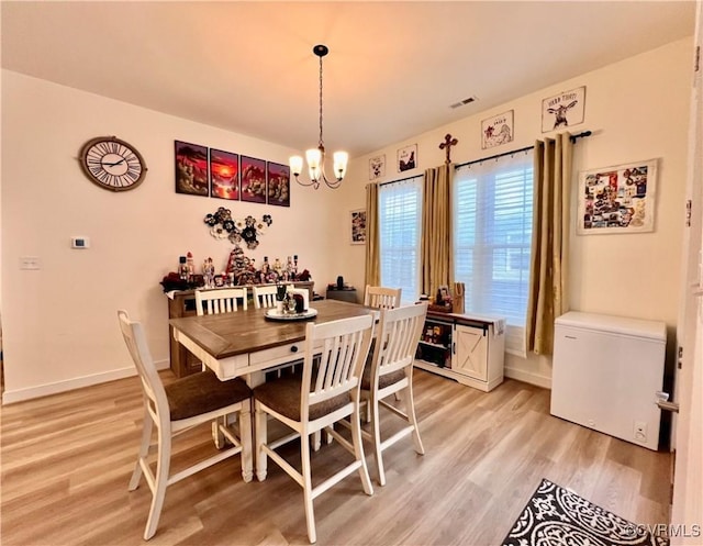 dining space with an inviting chandelier and light hardwood / wood-style flooring