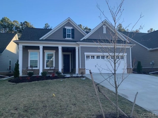 view of front of home featuring a garage, a front yard, and a porch