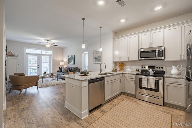 kitchen with hanging light fixtures, white cabinetry, sink, and stainless steel appliances