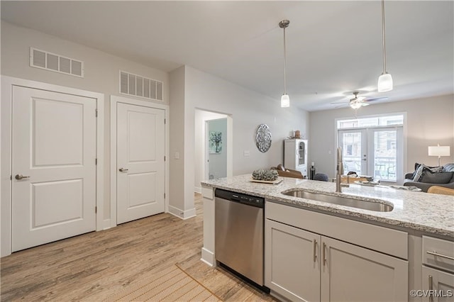 kitchen with sink, light stone counters, light hardwood / wood-style flooring, stainless steel dishwasher, and pendant lighting