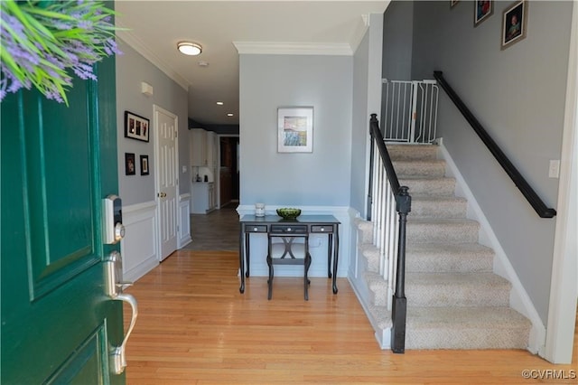 entryway with light hardwood / wood-style floors and crown molding