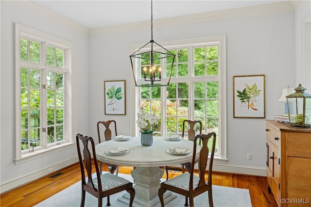 dining area with a healthy amount of sunlight, light hardwood / wood-style floors, and an inviting chandelier