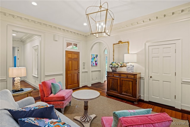 living room with a notable chandelier, dark hardwood / wood-style floors, and ornamental molding