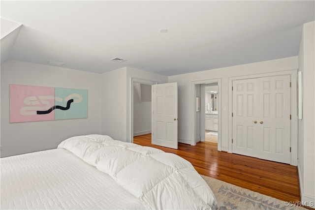 bedroom with hardwood / wood-style floors, connected bathroom, and a closet