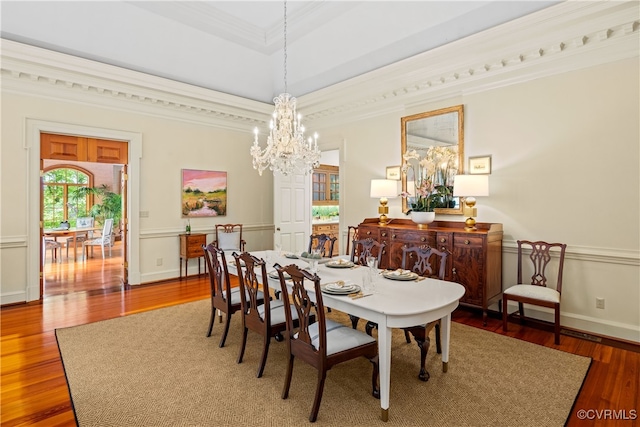 dining space featuring hardwood / wood-style flooring, crown molding, and an inviting chandelier