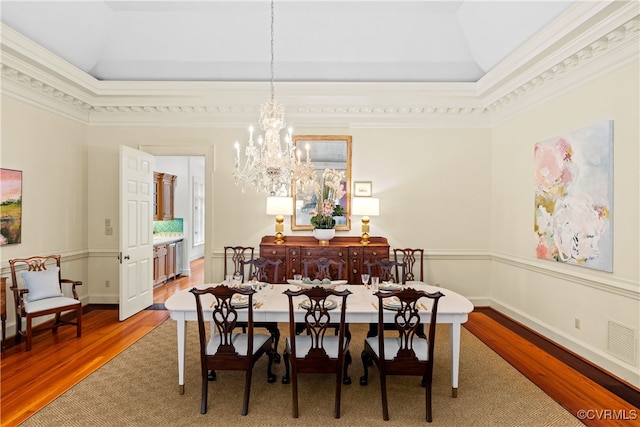 dining room featuring hardwood / wood-style flooring, lofted ceiling, ornamental molding, and a chandelier