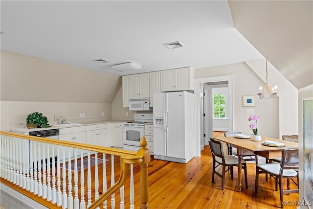 kitchen with lofted ceiling, white appliances, light hardwood / wood-style flooring, decorative light fixtures, and white cabinetry