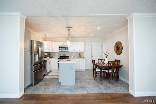 kitchen featuring a center island, white cabinets, light wood-type flooring, appliances with stainless steel finishes, and decorative light fixtures