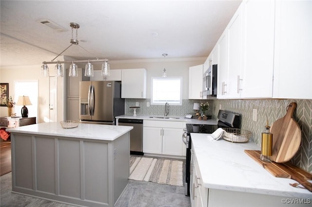 kitchen with white cabinets, appliances with stainless steel finishes, a center island, and decorative light fixtures