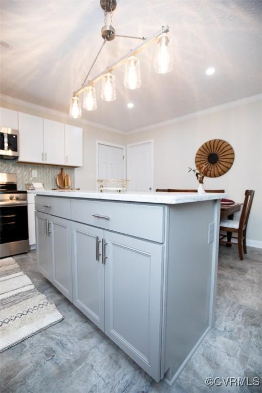 kitchen with hanging light fixtures, stainless steel appliances, tasteful backsplash, a kitchen island, and ornamental molding