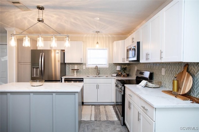 kitchen with sink, light stone counters, decorative light fixtures, white cabinets, and appliances with stainless steel finishes