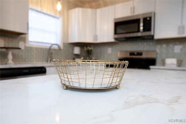 kitchen featuring white cabinets, range, and sink