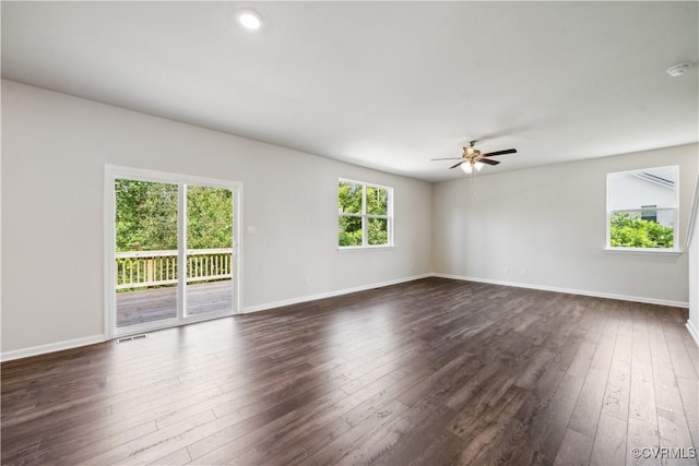 spare room featuring dark hardwood / wood-style floors, ceiling fan, and a wealth of natural light