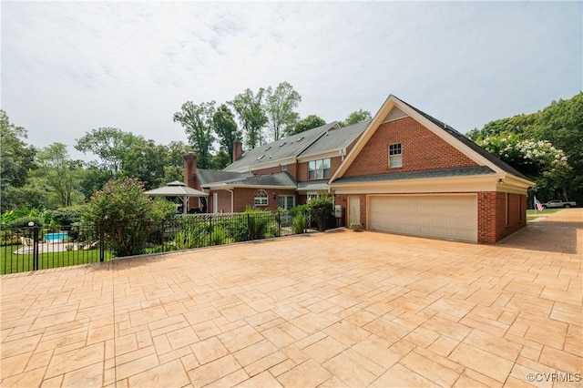 view of front of home with fence, decorative driveway, and brick siding