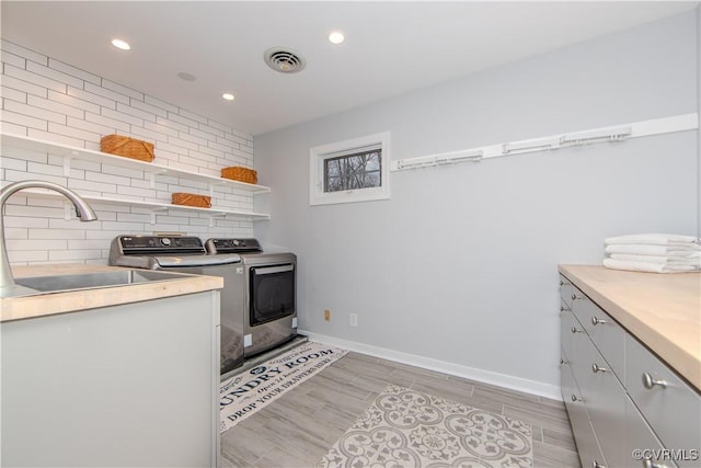 kitchen featuring washing machine and clothes dryer, open shelves, light countertops, visible vents, and a sink