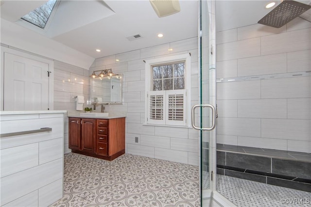 bathroom featuring tile walls, visible vents, vanity, tiled shower, and tile patterned floors