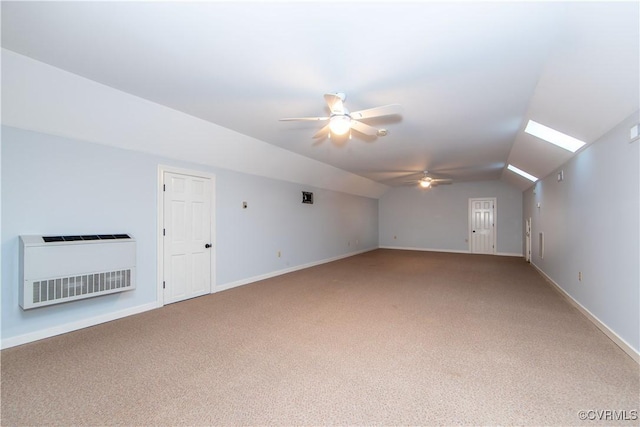 additional living space with vaulted ceiling with skylight, carpet floors, a ceiling fan, baseboards, and heating unit