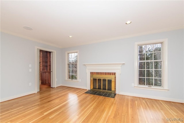 unfurnished living room featuring light wood finished floors, a fireplace, and crown molding