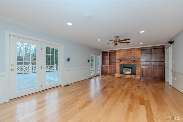 unfurnished living room with light wood-type flooring, plenty of natural light, built in features, and wainscoting